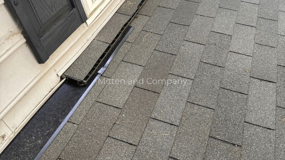 Close-up of asphalt shingles and metal flashing at window base
