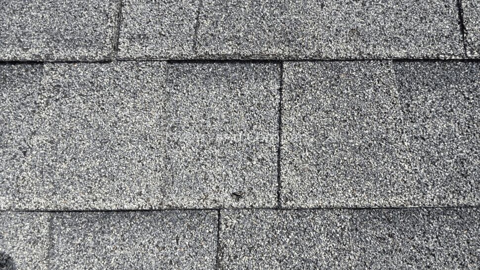 Close-up of asphalt shingle surface showing granules and seams.