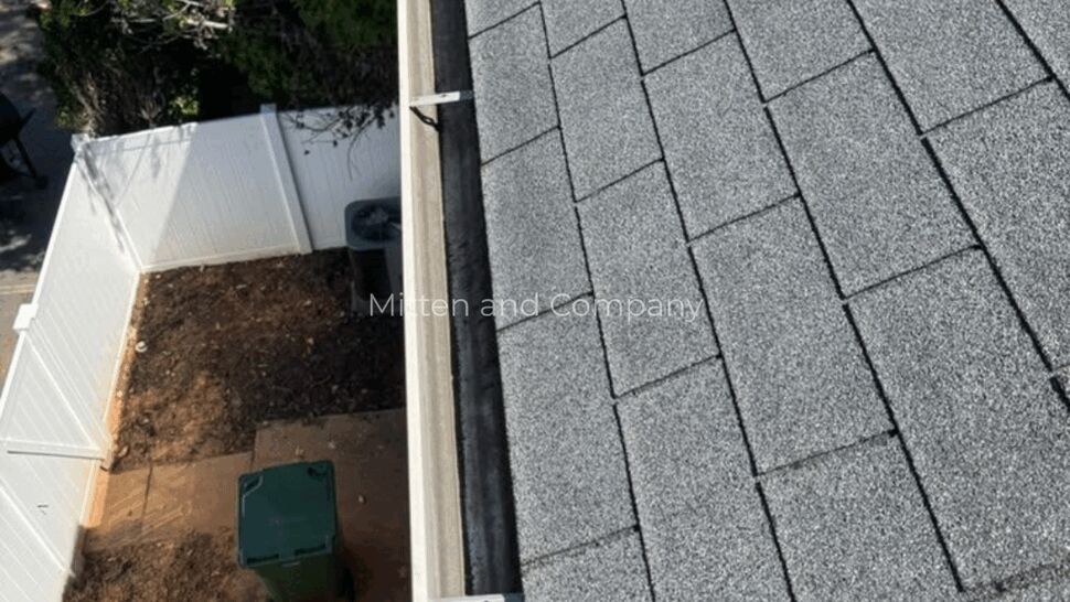 Shingle and Gutter Edge | Mitten & Company Gray asphalt shingles meet a white gutter along the edge of a home.