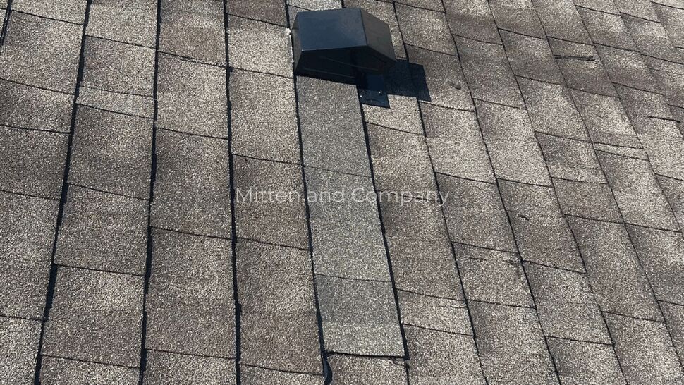 Roof vent installed on a broad field of gray asphalt shingles