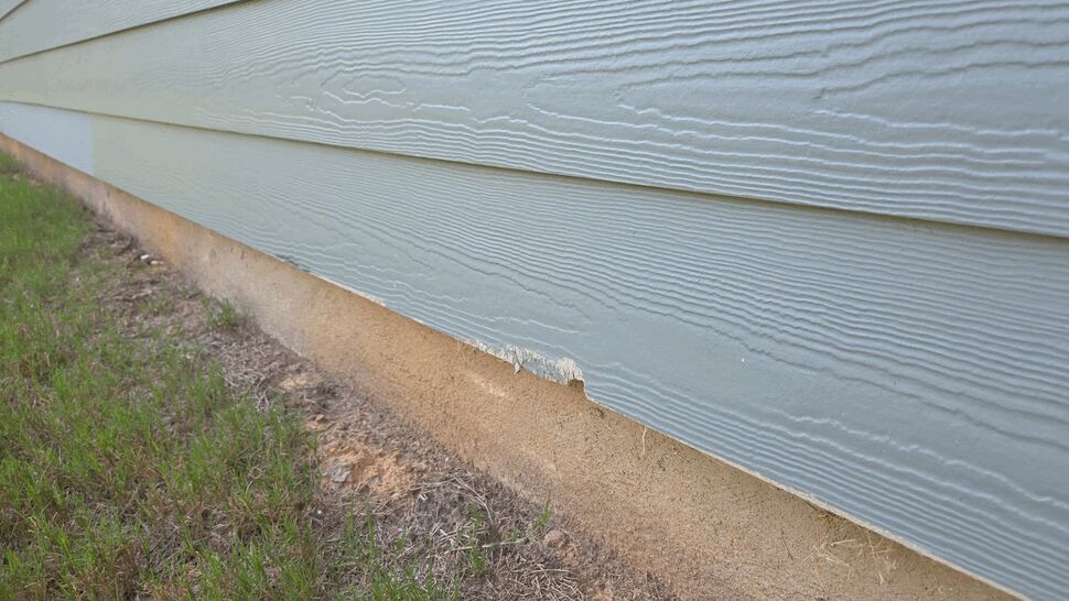 Close-up of Damaged Siding at Foundation | Mitten & Company Close-up of chipped siding at the foundation line