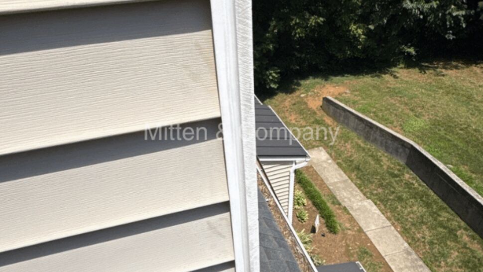 Side view showing vinyl siding, gutter and shingle roof below.