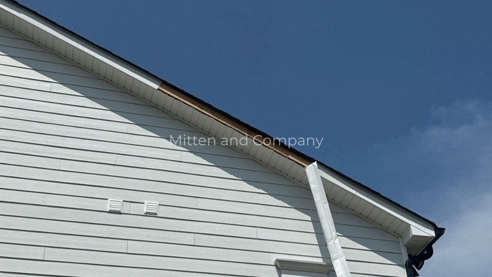 White downspout beside a window on a home with horizontal siding.