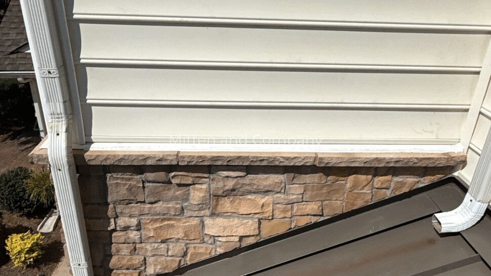 Siding, Stone, and Metal Roof Details | Mitten & Company White siding and stone veneer above a dark metal roof section