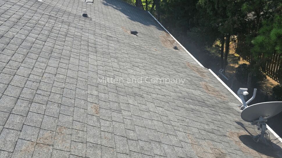Shingled roof slope with stained and worn shingles near vents