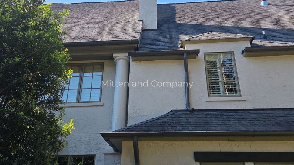 Stucco Home Roof and Chimney Inspection | Mitten & Company Two-story stucco home with steep shingle roof, chimney and black gutters.