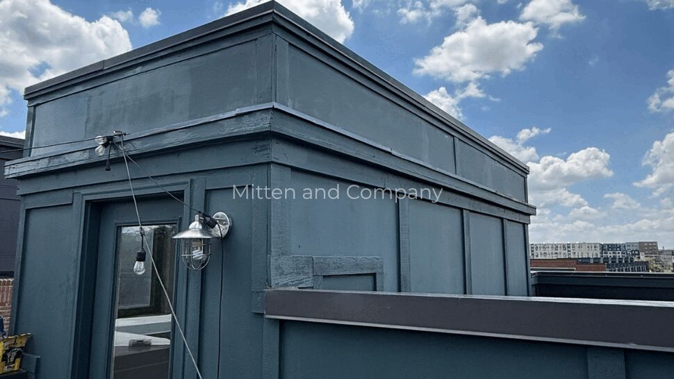 Teal rooftop access structure with string lights under a blue sky