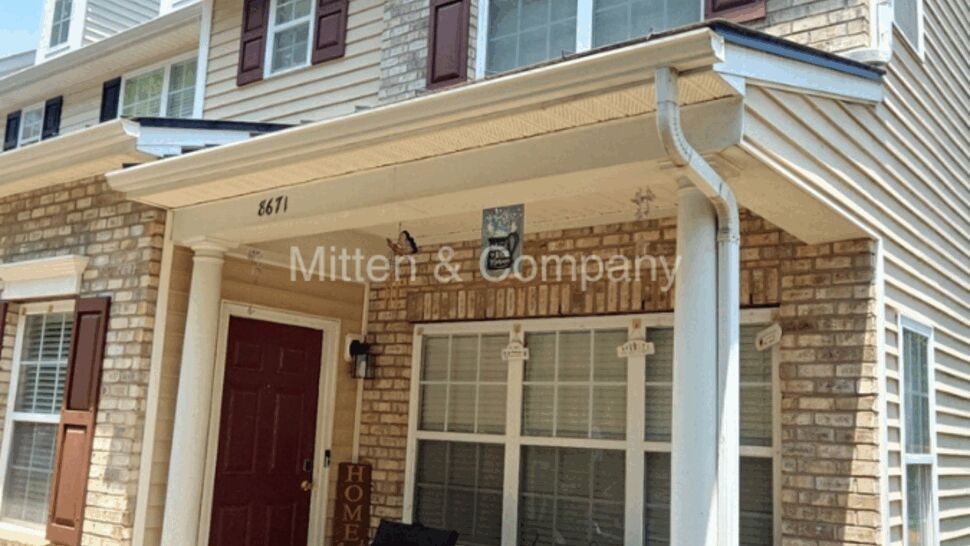 Front porch of a townhome showing gutter, column, brick and siding.