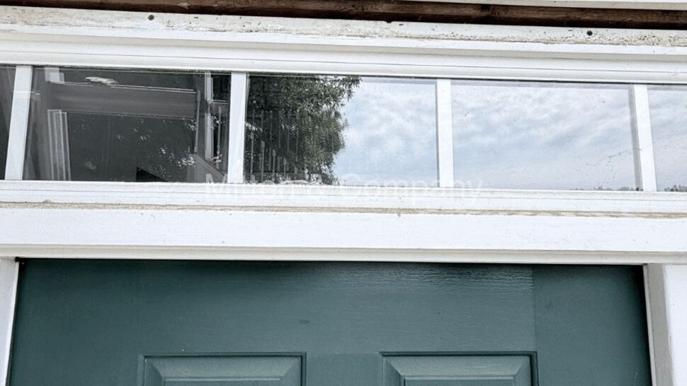 Transom window above door with exposed sheathing and weather wrap