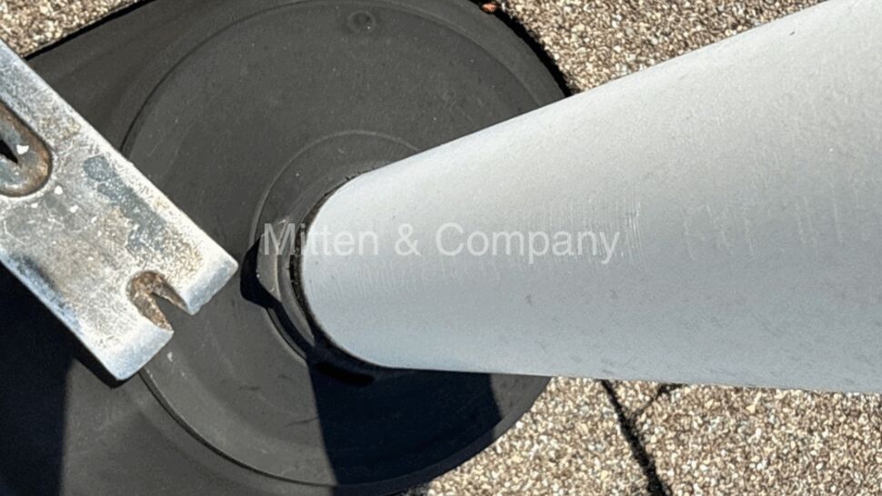 Close-up of rubber roof vent boot and white vent pipe with mounting bracket