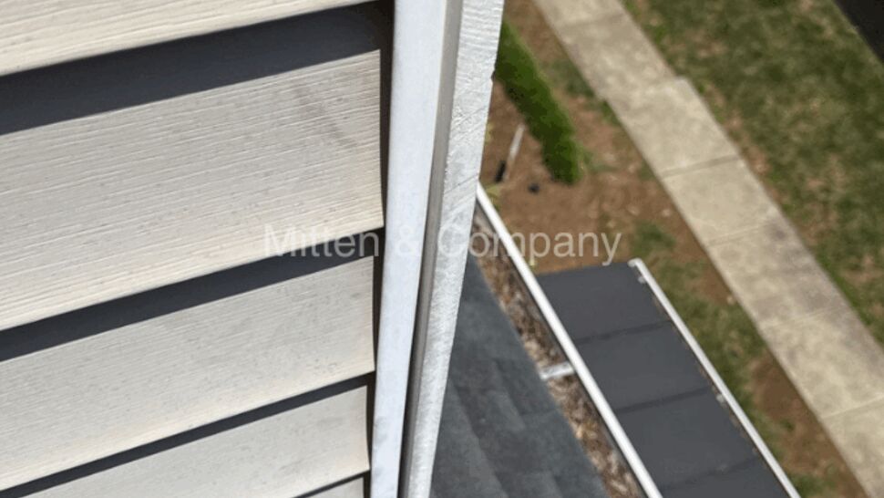 Close-up of vertical siding edge with gutter and roofline below.