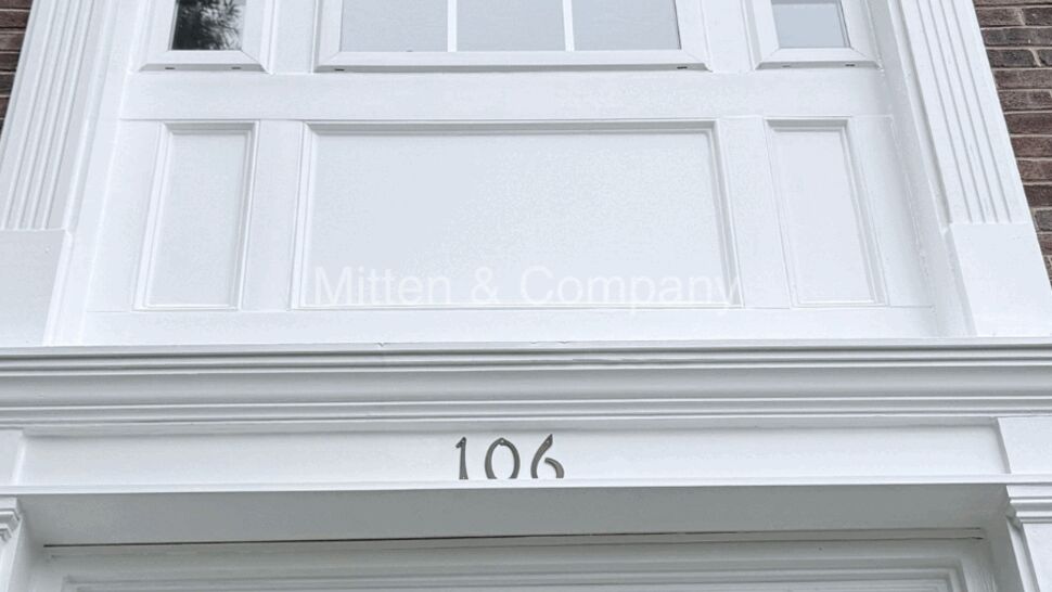 White bay window and decorative entrance trim with house number 106