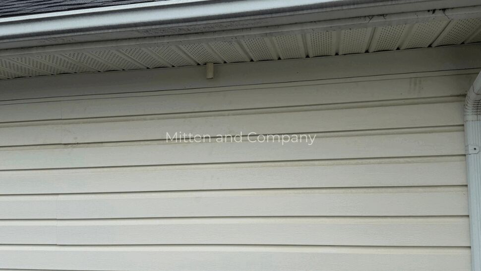 White Siding and Roofline Exterior | Mitten & Company White horizontal siding beneath dark roof shingles and a gutter