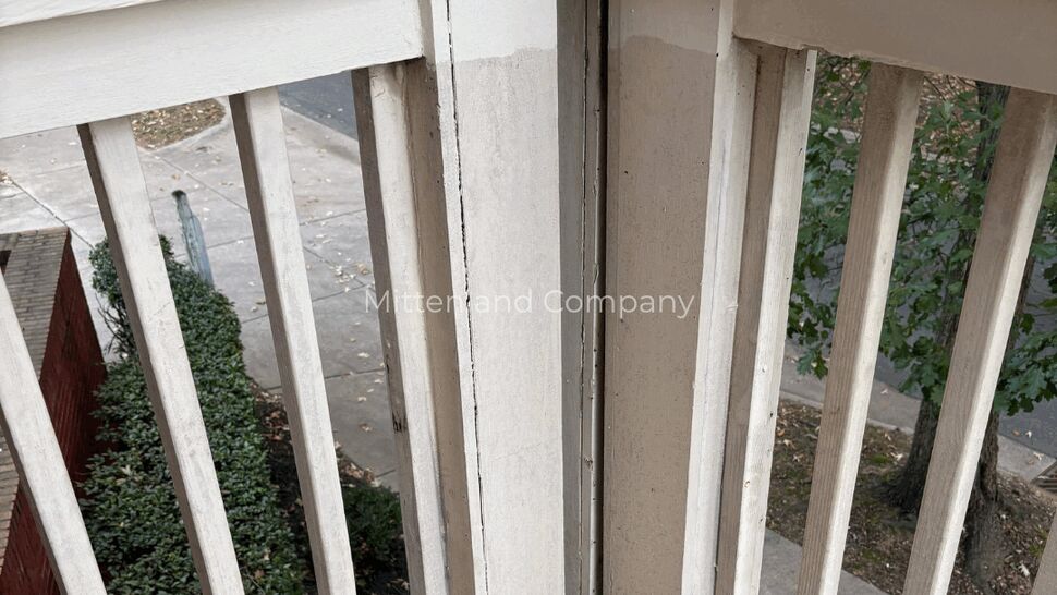 White Porch Railing Corner | Mitten & Company Close-up of a white porch railing corner and wooden deck boards