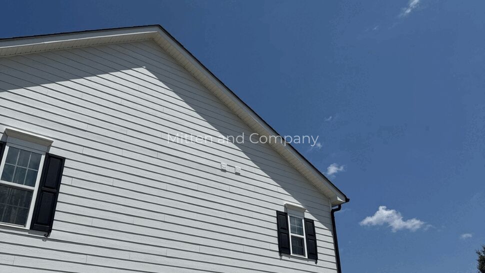 White horizontal siding on a home gable beneath a blue sky.