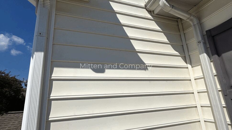 White Siding and Gutter Corner | Mitten & Company White horizontal siding, soffit, and downspout on a home exterior