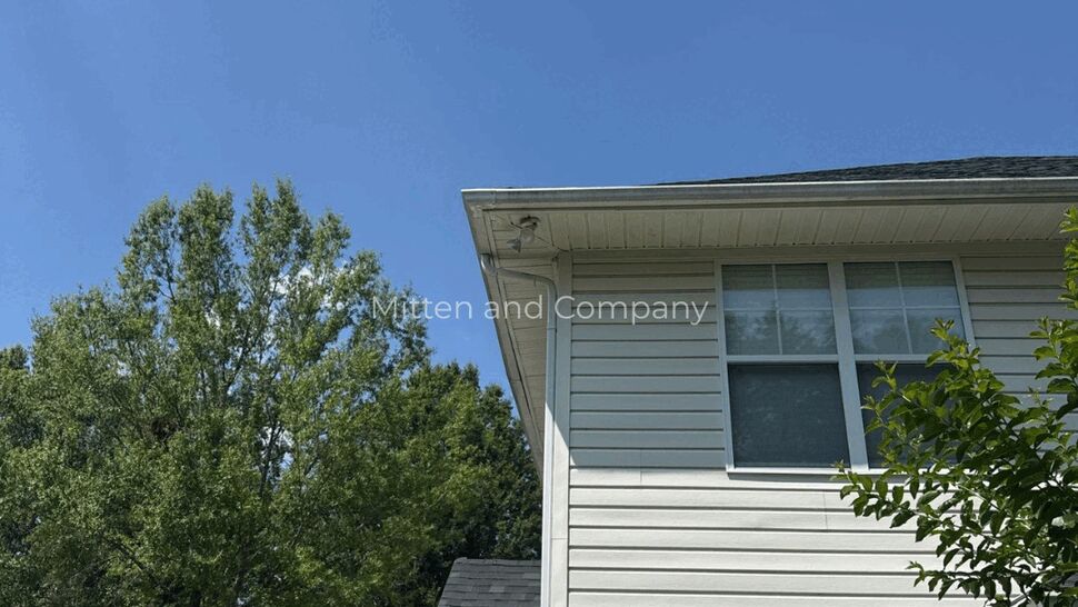Corner view of two-story white vinyl siding and soffit under blue sky