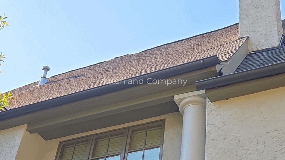 Window and Gutter Roof Interface | Mitten & Company Upper window with white column and dark gutter beneath shingled roof.