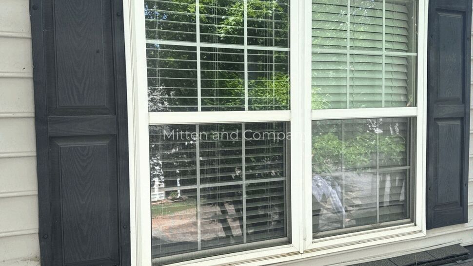 Window Flashing Inspection After Storm | Mitten & Company Double window with black shutters above roof shingles and flashing