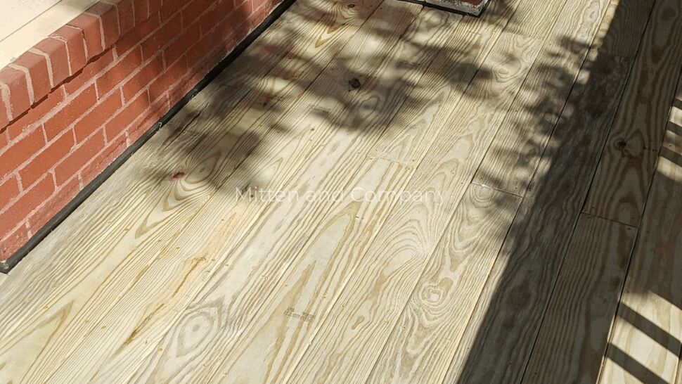 Wood Porch Floor and Brick Wall | Mitten & Company New wood porch flooring beside a red brick wall and window