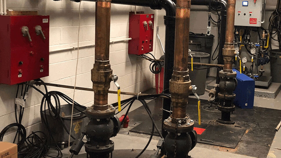 Mechanical room with copper and cast-iron pumps, valves, and control boxes