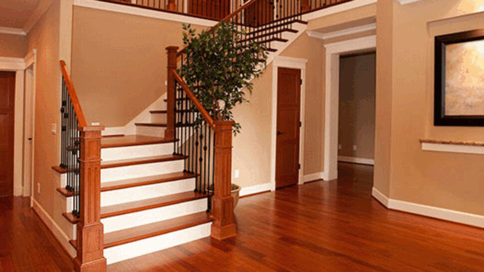 Spacious foyer with polished hardwood floors and a staircase with wood posts and iron balusters.