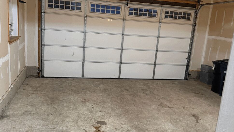 Interior garage with concrete floor, unfinished walls, and opener