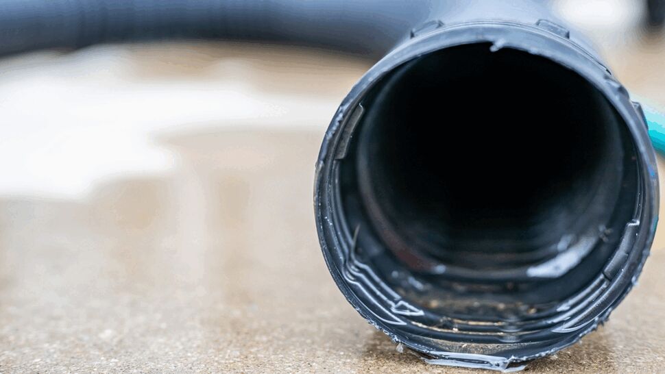 Close-up of a black plastic drain pipe on wet concrete