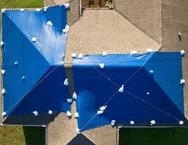 Aerial view of a house roof covered with blue tarps and sandbags.