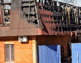 Commercial building with a collapsed, burned roof and exposed structural framework.