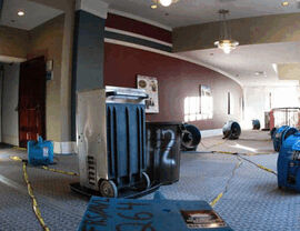 Large commercial interior with multiple air movers and drying equipment in place.