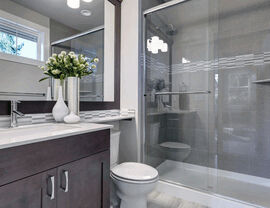 Dark wood vanity beside a glass-enclosed shower with accent tile