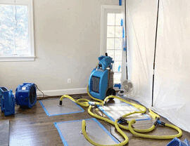 Drying equipment and yellow hoses on hardwood floor with plastic containment