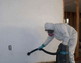 Worker in suit using a HEPA vacuum to clean contaminated floor and wall surfaces