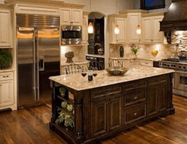 Large kitchen with central dark wood island, granite countertop, cream cabinetry and stainless appliances.