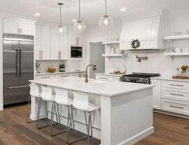 Modern all-white kitchen with large island and bar stools