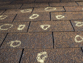 Brown shingles covered with numerous chalk circles indicating hail impacts