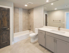 Modern bathroom with bathtub, tiled shower accent and gray vanity