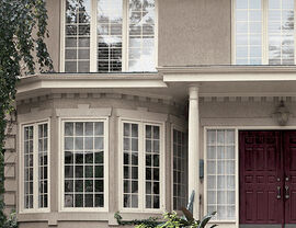 Two-story home with bay windows, decorative columns and a red double door.