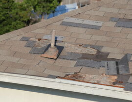Roof vent flashing with surrounding torn shingles and rotted roof decking at the eave.
