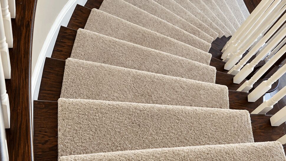 Carpeted Stair Flooring | TSP Contracting Curved staircase with beige carpet runners over dark wood flooring