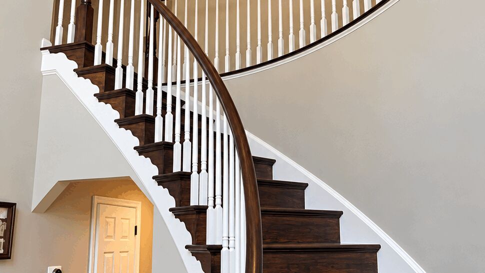 Curved Staircase Remodel | TSP Contracting Curved staircase with dark wood steps, white spindles, and polished handrail
