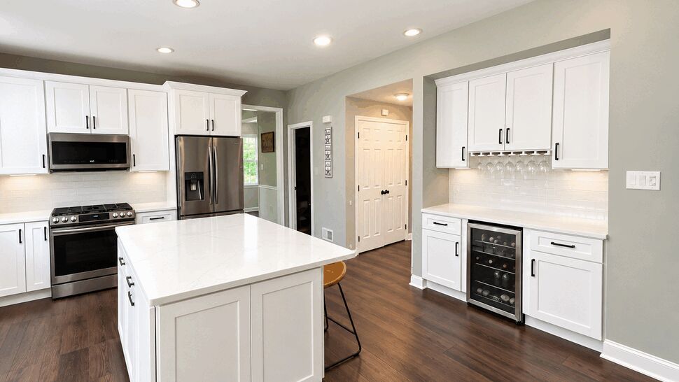 Modern White Kitchen Design | TSP Contracting Modern white kitchen with island, stainless appliances, wine cooler, and wood floors