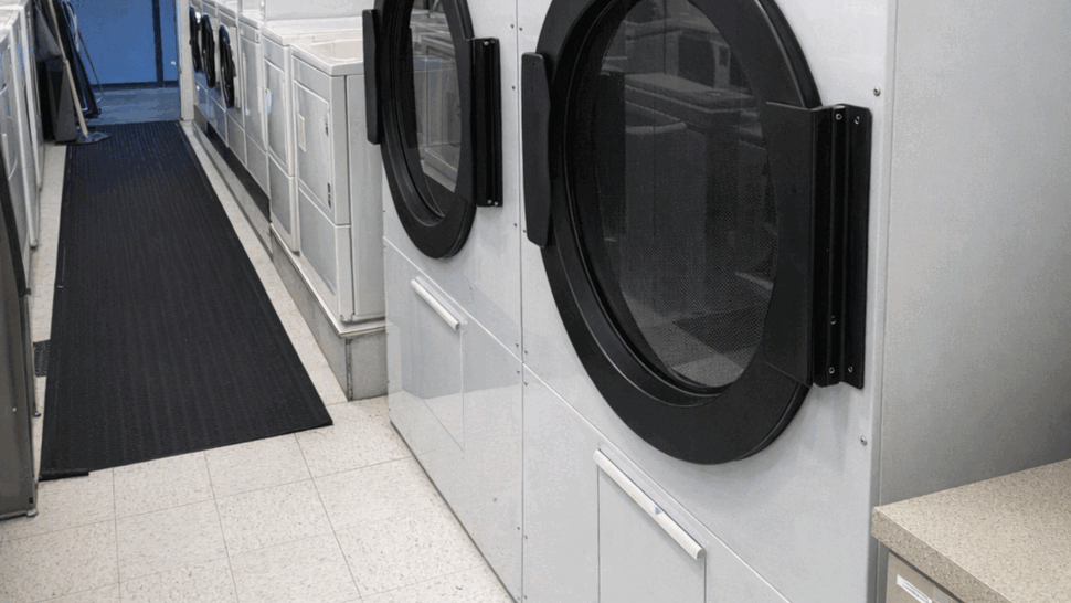 Commercial laundry room with large front-load dryers and washers along a corridor