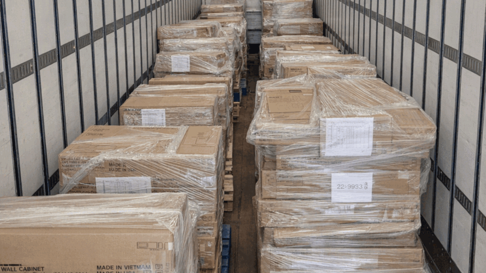 Rows of shrink-wrapped pallets lined down the center of a moving trailer.