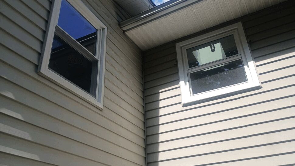 Two corner upper windows on beige siding with soffit above