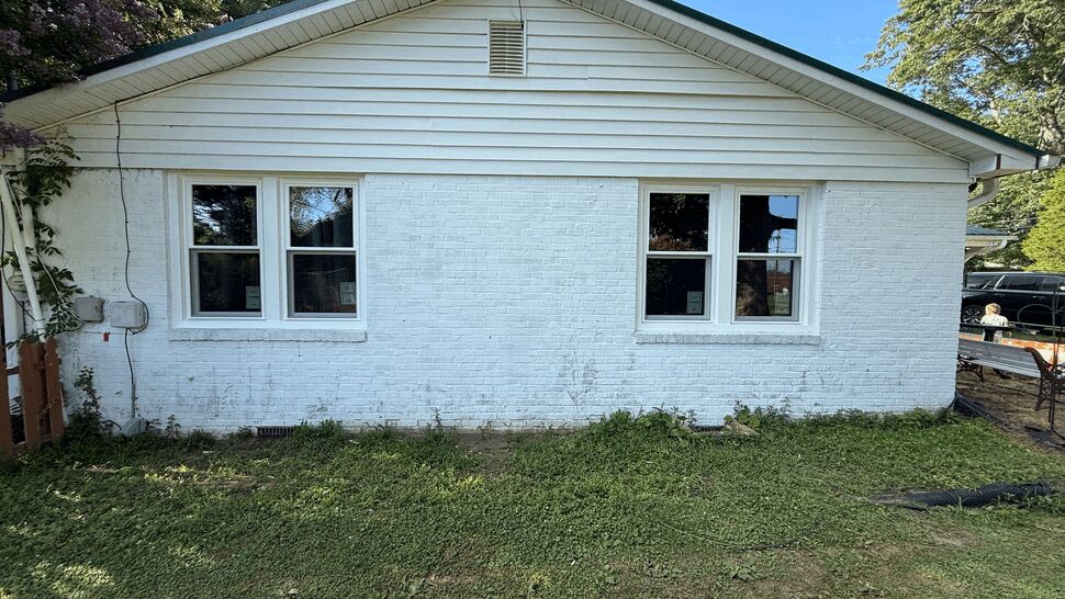 Front exterior of a white brick house showing two identical double-window sets