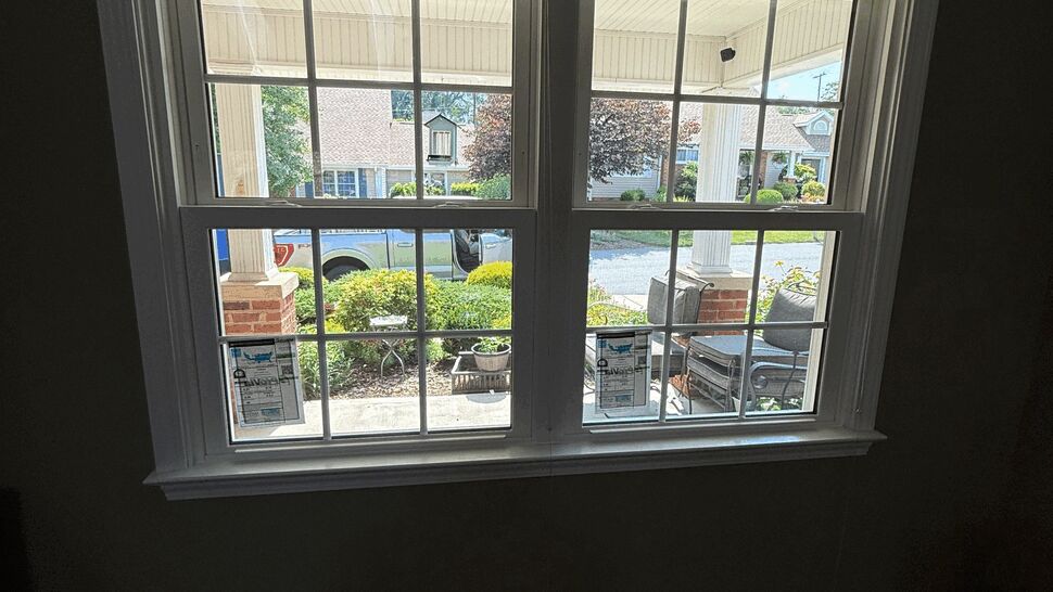 Interior view of white double-hung windows with divided lights looking onto porch