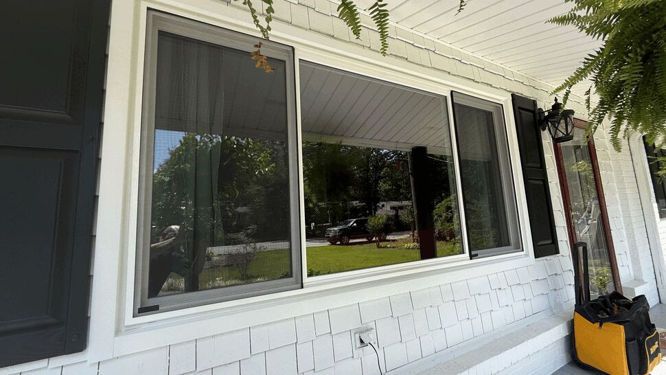 Large porch picture window with sliding panels and white frame under porch roof