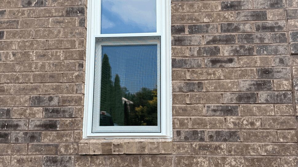 Tall narrow single sash window set in brick wall